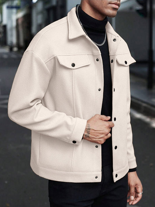 Person wearing a white denim jacket over a black shirt on a blurred street background